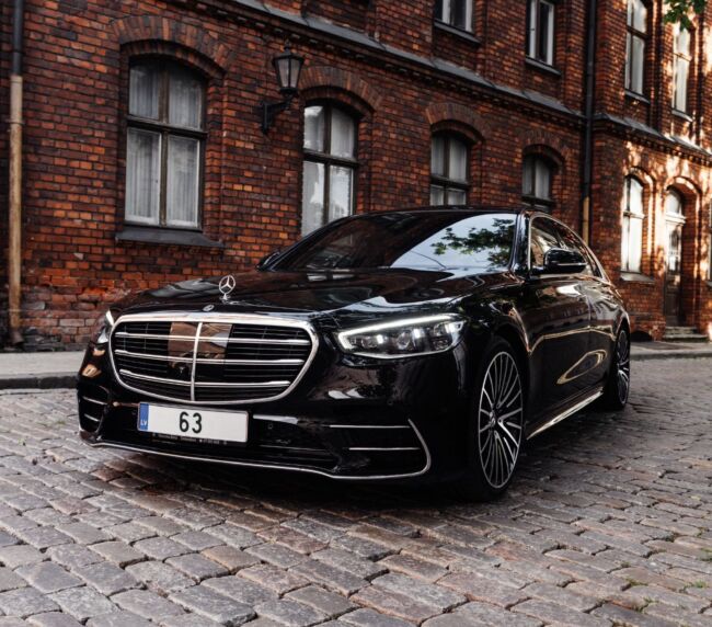 Black luxury car, a Mercedes parked in front of modern urban buildings