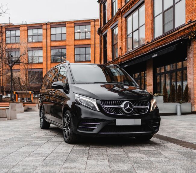 Black luxury Mercedes van parked in front of modern urban buildings