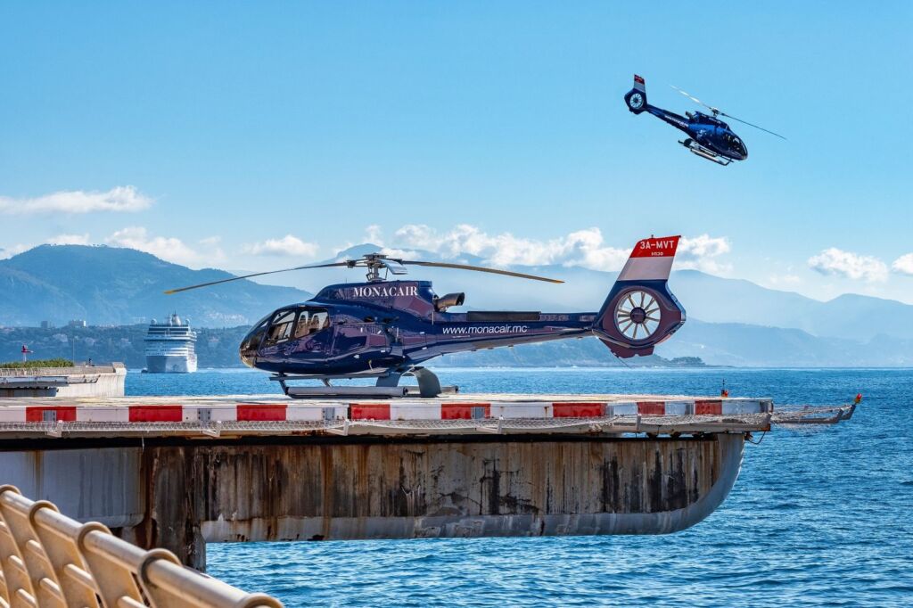 Luxury Monacair helicopter on seaside helipad with mountains in background