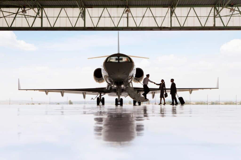 Passengers being welcomed aboard a private jet inside an aircraft hangar