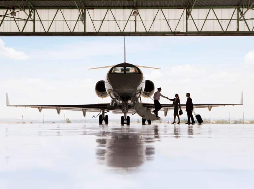 Passengers being welcomed aboard a private jet inside an aircraft hangar